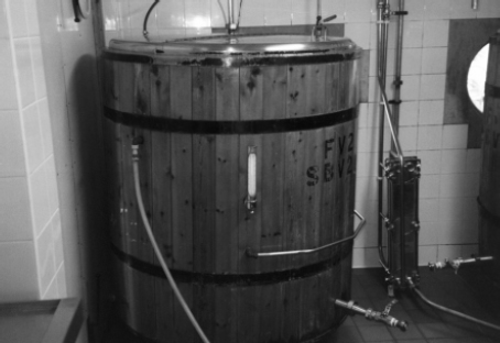 Fermenting vessel with thermometer and cooling jacket (between black bands). The brewery's heat exchanger (wort cooler) is pictured to the right.